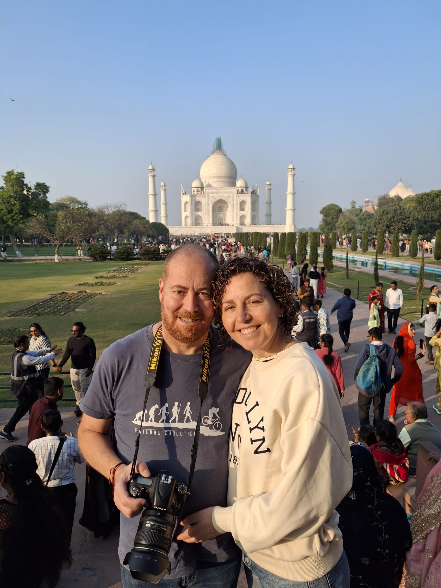 El Taj Mahal aparece al fondo entre jardines y visitantes.